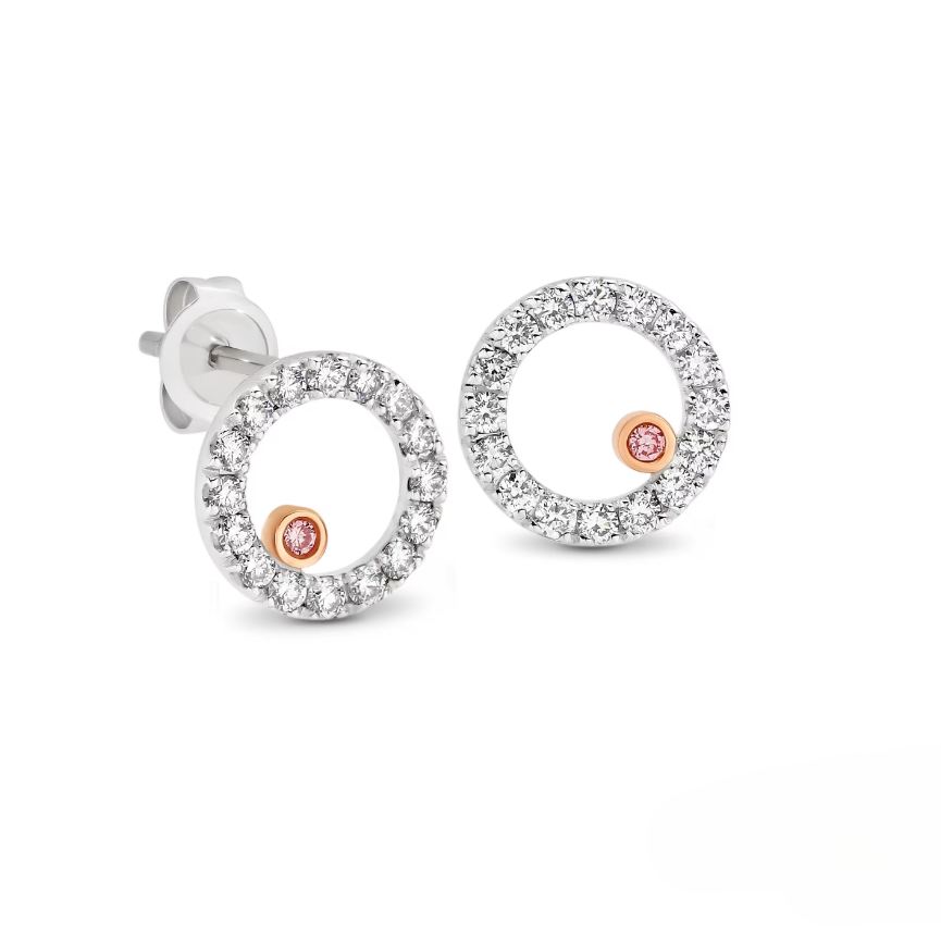Pair of white gold earrings with circular claw set diamonds with a offset feature australian pink diamond on a white background